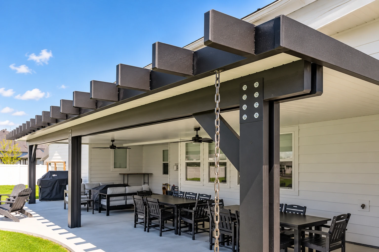 Covered patio with a dark timber pergola, ceiling fans, and outdoor dining and lounge furniture.